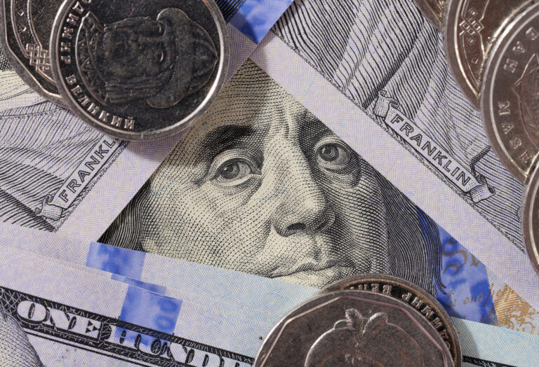 Fragment of one hundred dollar bill with a portrait of Benjamin Franklin under a magnifying glass, eye